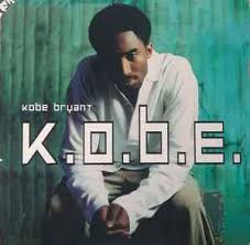 Kobe Bryant in a sweater sitting down and clasping his hands, looking straight ahead at the viewer.